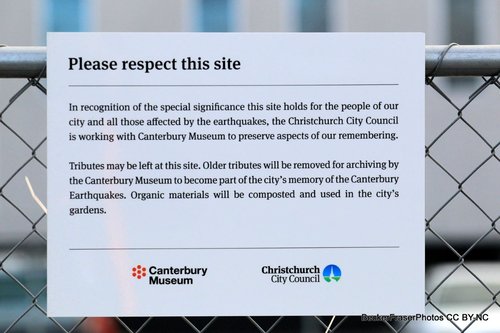 A notice on the fence outside the CTV site on Madras Street. The notice reads, "Please respect this site. In recognition of the special significance this site holds for the people of our city and all those affected by the earthquakes, the Christchurch City Council is working with Canterbury Museum to preserve aspects of our remembering. Tributes may be left at this site. Older tributes will be removed for archiving by the Canterbury Museum to become part of the city's memory of the Canterbury Earthquakes. Organic materials will be composted and used in the city's gardens. Canterbury Museum. Christchurch City Council".