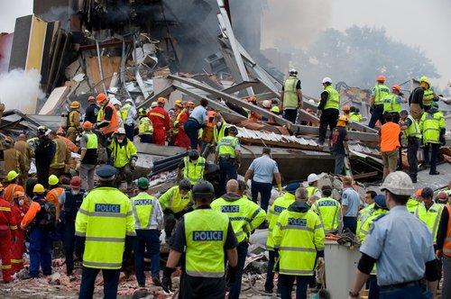 Emergency personnel searching for people trapped in the collapsed Canterbury Television Building on Madras Street. Smoke can be seen rising from the ruins.
